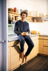Mann in blauer Loungewear hält einen Becher