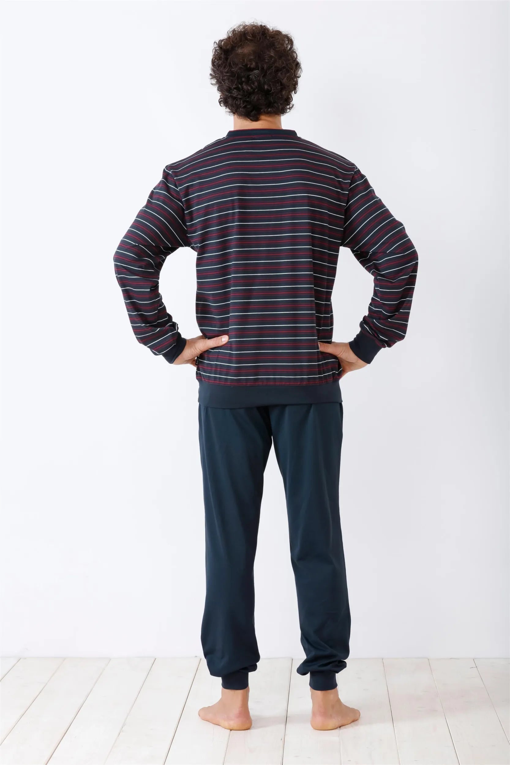 Eine Person von hinten, die ein dunkles gestreiftes langärmeliges Hemd und eine dunkle Jogginghose trägt.