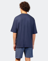 Marineblaues, übergroßes T-Shirt mit einer Tasche und geripptem Saum, wahrscheinlich aus Baumwolle oder einem Polyestergemisch.