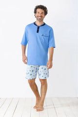 Hellblaues kurzärmeliges Herren-Pyjama-Oberteil mit dunkelblauer Knopfleiste und Tasche, kombiniert mit hellblau gemusterten Pyjama-Shorts.