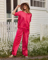 Rosa Seidenpyjama mit passendem breitkrempigen Hut und Sandalen.