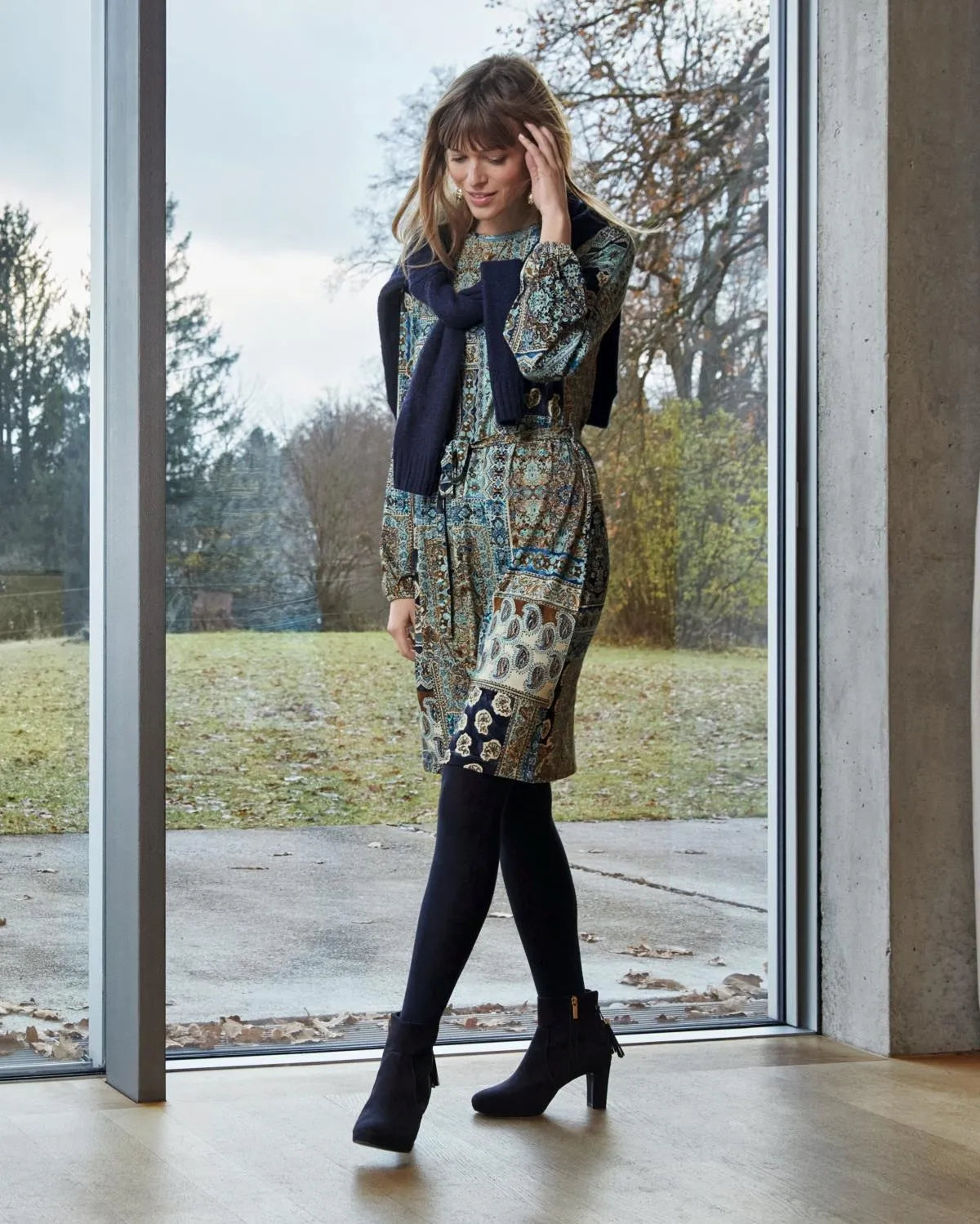 Knielanges Kleid mit Blumenmuster, schwarzer Strumpfhose und Ankle Boots.