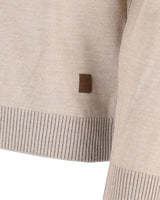 Beigefarbener Pullover mit gerippten Abschlüssen und einem braunen Lederanhänger.