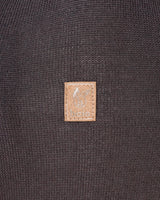 Brauner Lederaufnäher mit Logo auf dunklem Strickstoff.