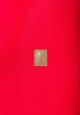 Goldfarbener quadratischer Stempel oder Siegel auf roter Oberfläche.