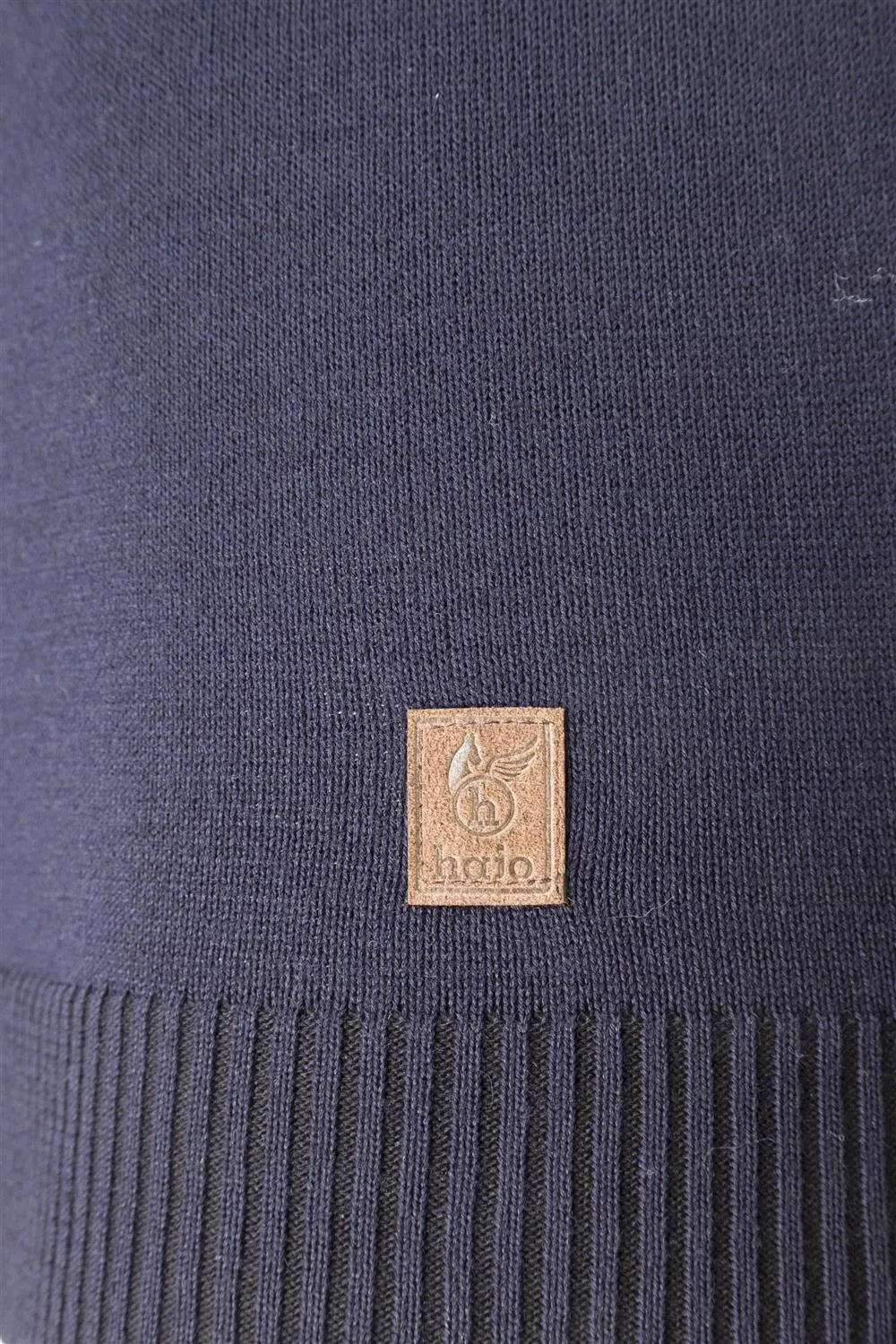 Marineblauer Strickstoff mit einem kleinen kupferfarbenen quadratischen Logoaufnäher.