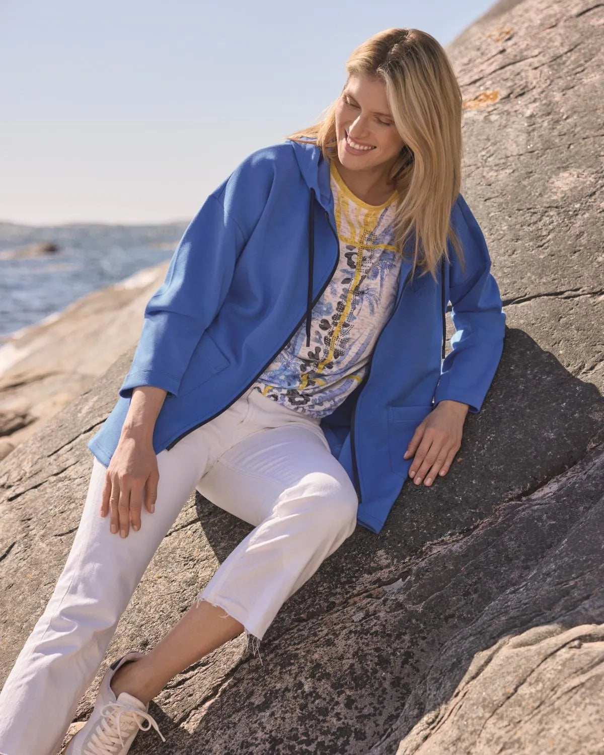 Blauer Baumwollblazer mit weißer Hose und Turnschuhen.