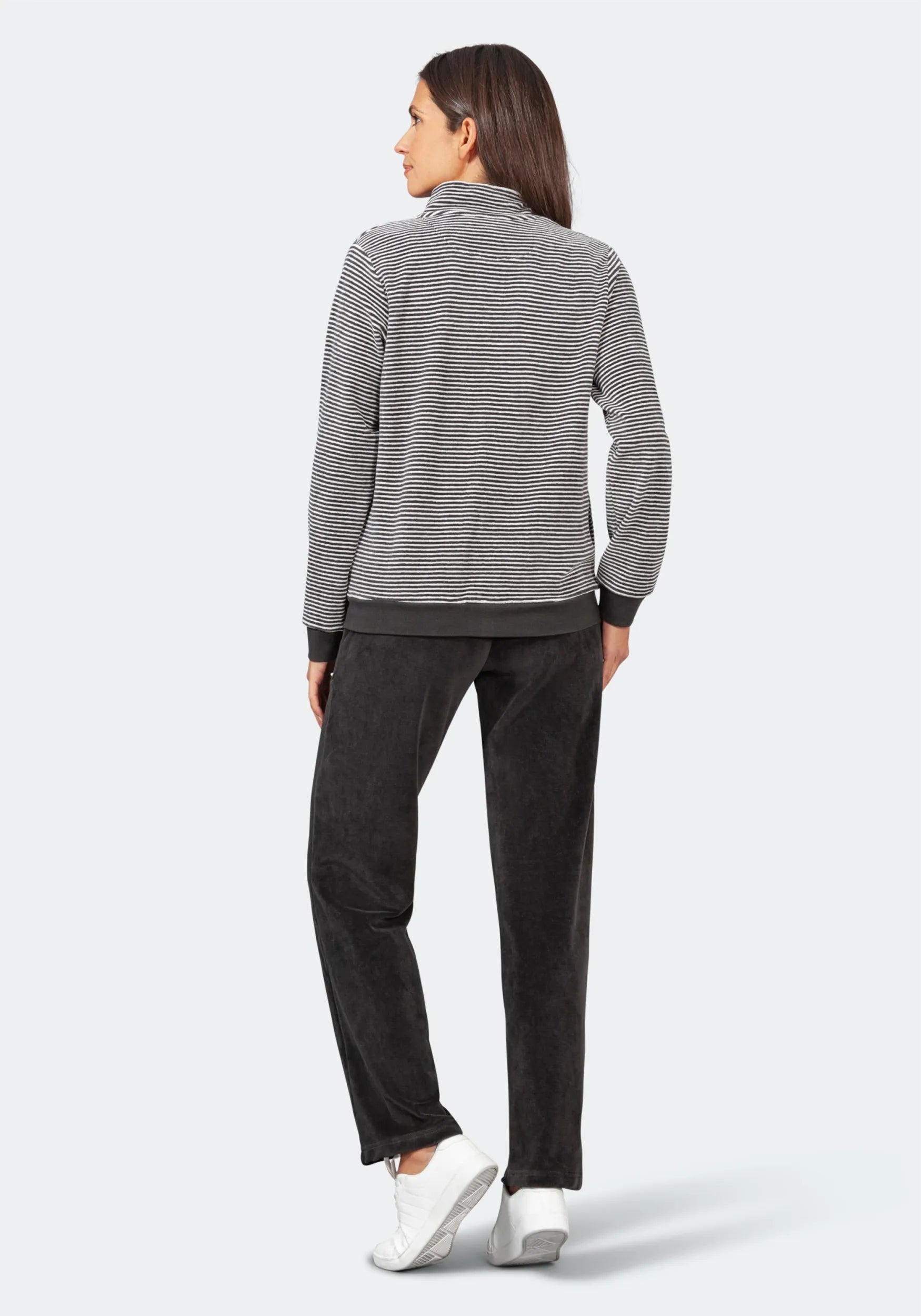 Gestreifter Pullover mit schwarzer Hose und weißen Sneakers.