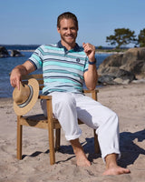 Gestreiftes Poloshirt mit weißer Hose und Strohhut.