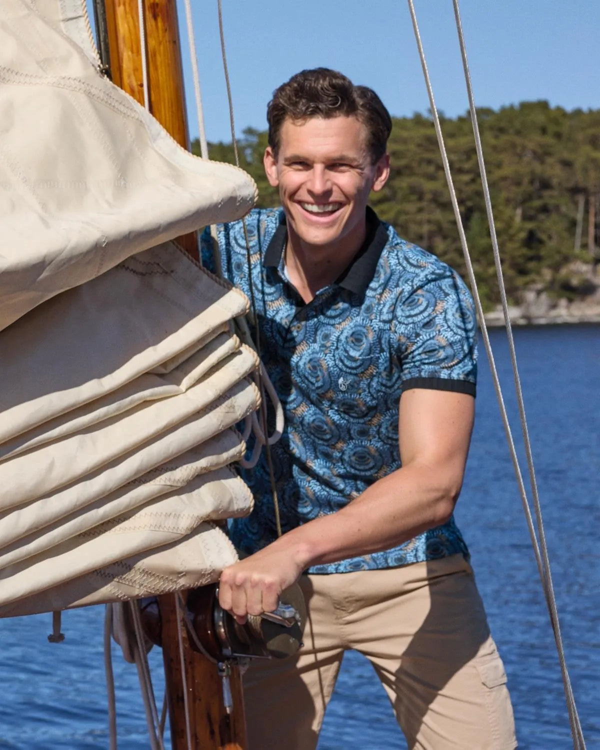 Blau gemustertes Poloshirt mit weißem und schwarzem Muster, khakifarbene Hose.