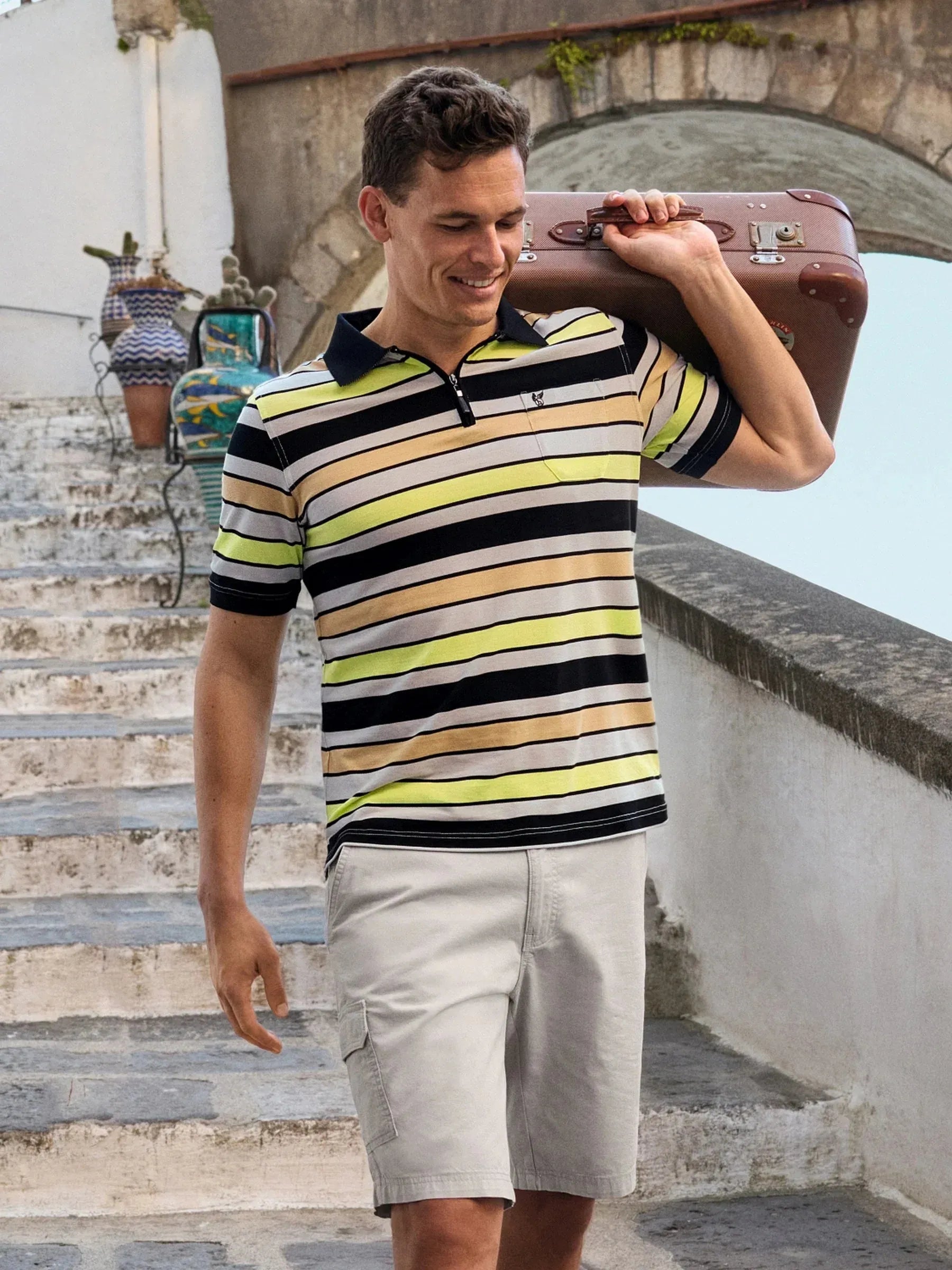 Mann in Pikeepolo mit schräg gestreiftem Allover-Muster in Schwarz, Gelb, Beige