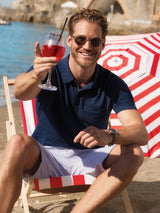 Mann in strukturiertem Stay Fresh Poloshirt und gestreiften Shorts auf Strandstuhl