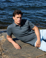 Poloshirt mit strukturiertem Muster, dunkelgrau, kurze Ärmel und hellblaue Jeans.