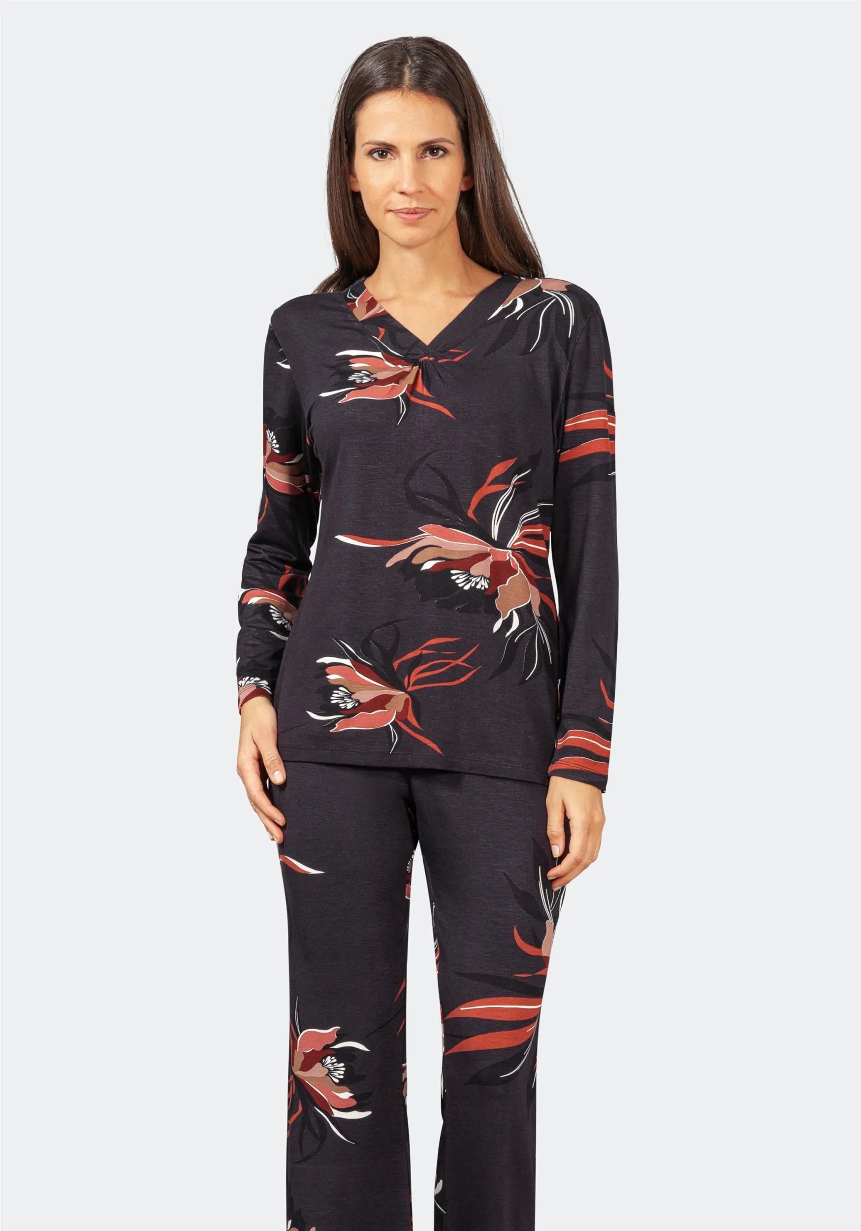 Zweiteiliges Pyjama-Set für Damen mit einem schwarzen, langärmeligen Oberteil mit V-Ausschnitt und einer dazu passenden Hose, beide mit einem lebhaften Blumenmuster in Rot-, Weiß- und Brauntönen verziert.