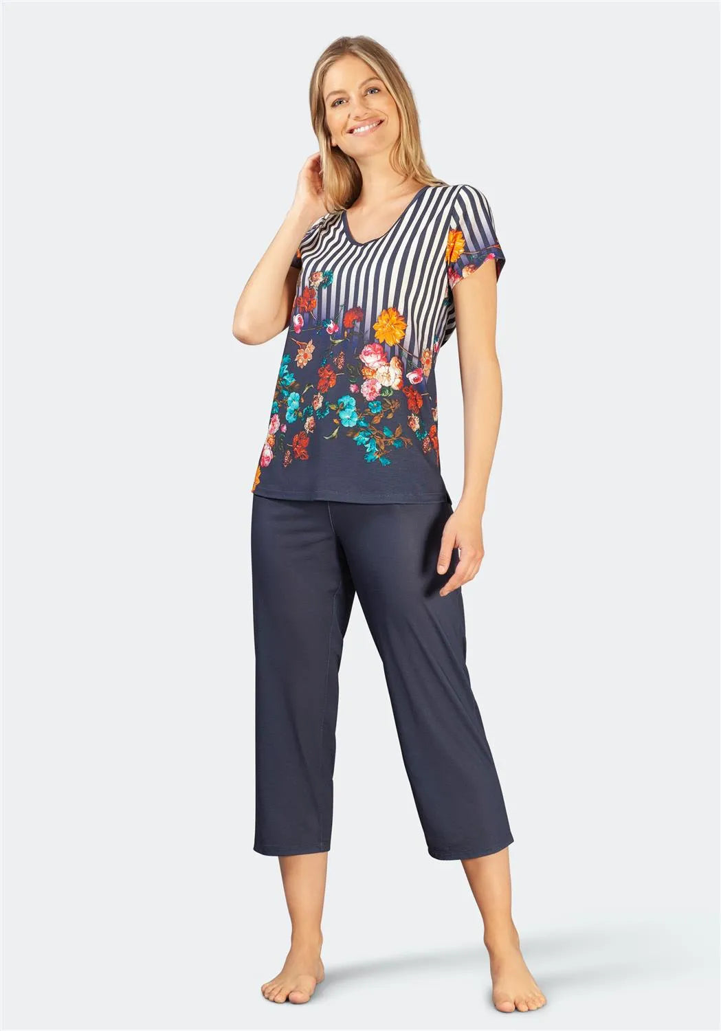 Gestreifter Schlafanzug mit Blumendruck, marineblauer Hose und buntem Blumenmuster auf dem Oberteil.