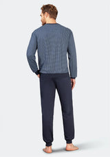 Blaugrau gemustertes, langärmeliges Herren-Pyjama-Oberteil und dunkelblaue, unifarbene Pyjama-Hose mit Bündchen an den Knöcheln.