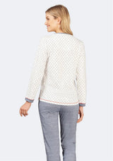 Cremefarbener und weiß gemusterter Pullover mit grauer Hose.