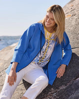 Blauer Baumwollblazer mit blumengemustertem Hemd und weißer Hose.