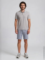 Ein mann trägt eine hellblaue strukturierte bermudashort mit elasthan und ein hellgraues polohemd von hajo mode