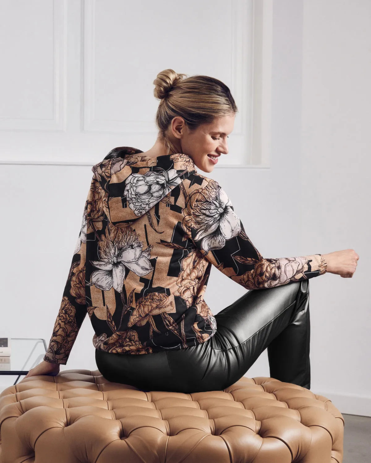 Damen-Kapuzenpulli mit Blumendruck und schwarze Kunstlederhose.