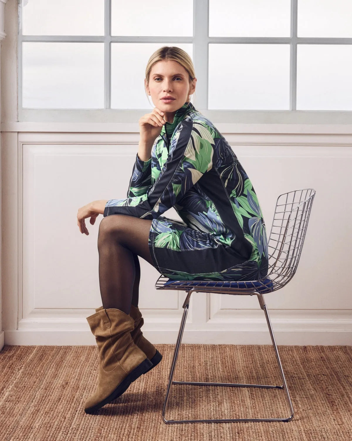 Frau in einem Kleid mit tropischem Muster und braunen Schlabberstiefeln.