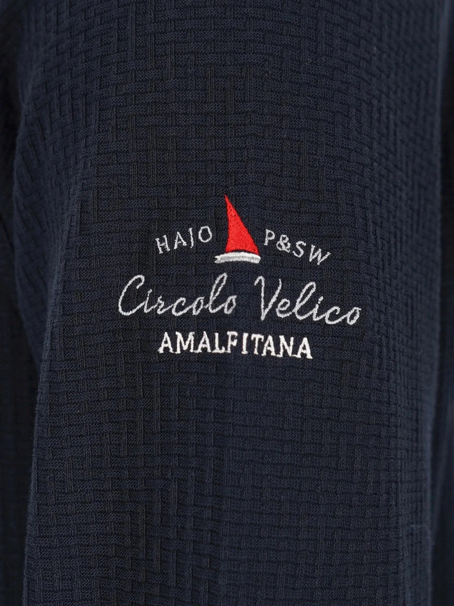Marineblaue strukturierte Jacke mit rotem Segelboot-Logo und weißem Text.