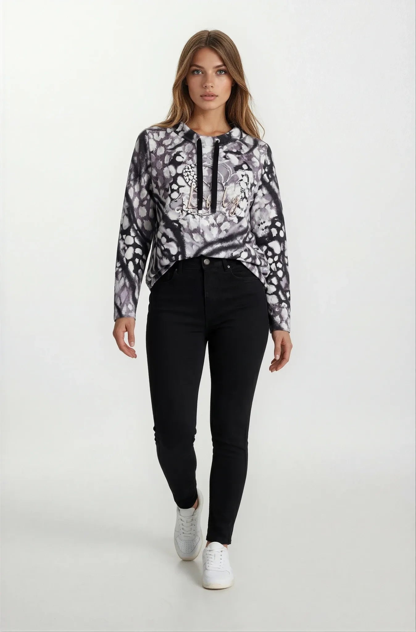 Frau in schwarzem-weiß gemustertem Hoodie mit Floraldesign und Zierbändern